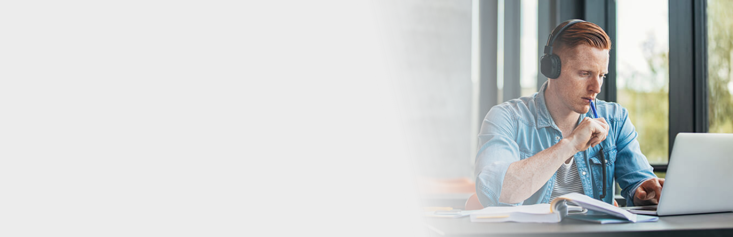 red haired male student studying on laptop