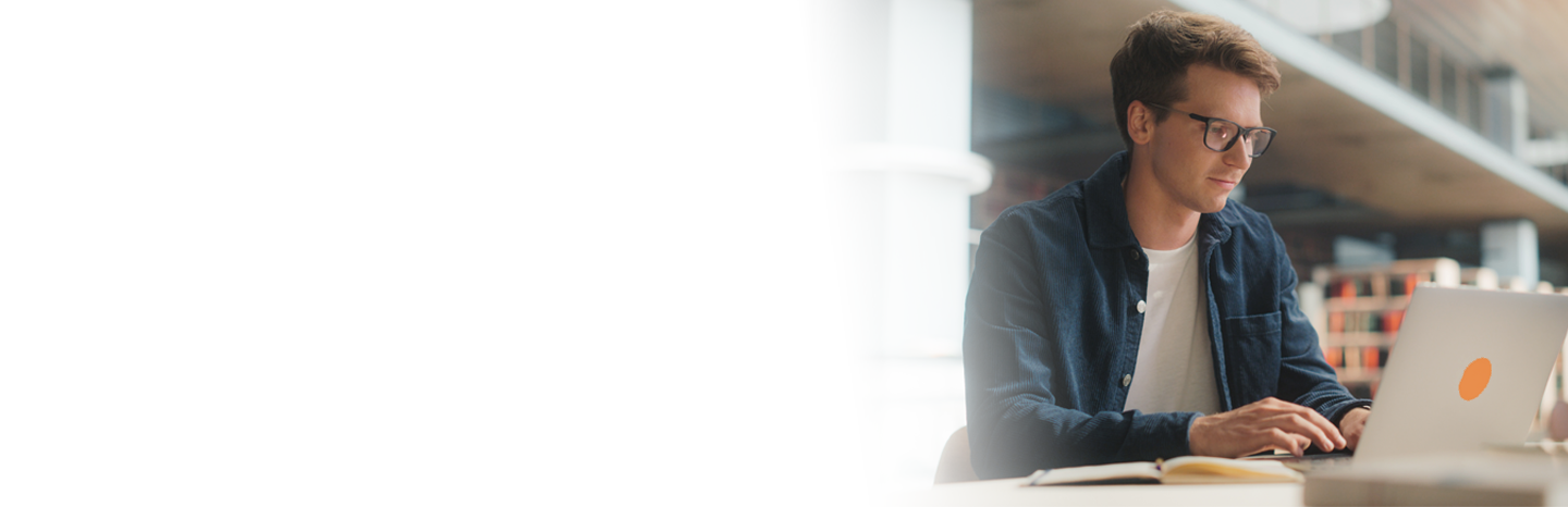 Young man sitting in a library typing on his laptop