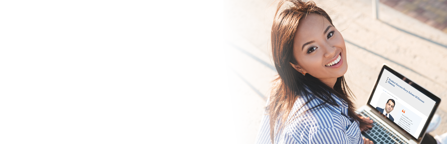 Young woman outside looking up from her laptop 