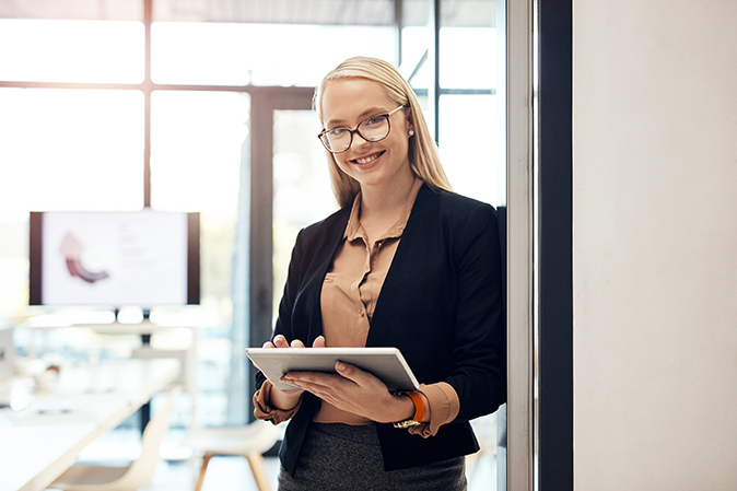 Young professional woman holding a tablet in an office doorway